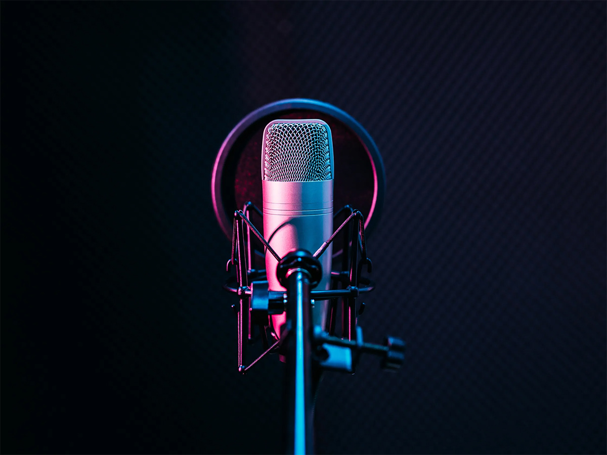 Image of a podcast microphone against a blue backdrop.
